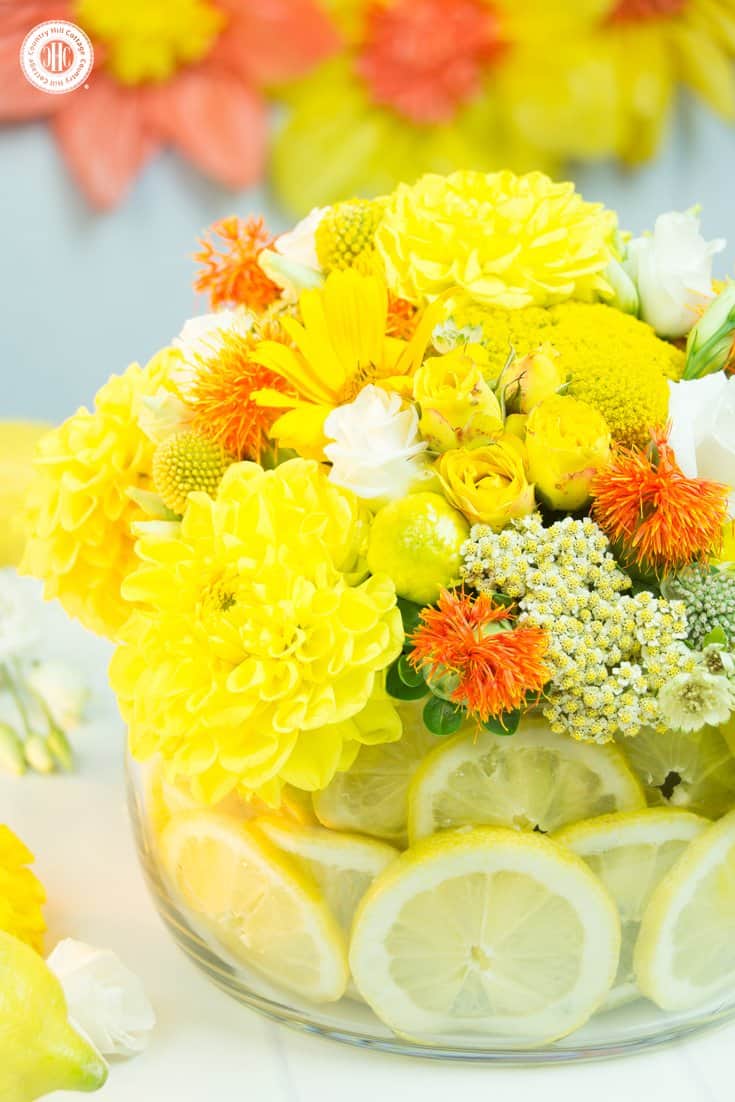 Learn to make a stunning yellow centrepiece with lemons! Lemons add a pop of colour and visual interest plus hide the floral foam that holds the flowers. #flowerarrangement #lemons #centerpiece | countryhillcottage.com