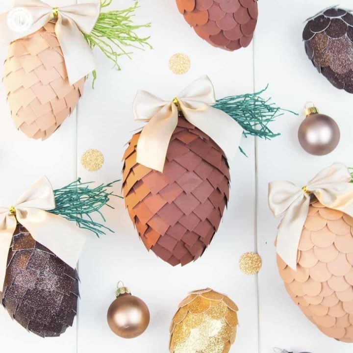 Learn how to make paper pinecone ornaments that you can use to decorate your Christmas tree or for packaging gifts. The ornaments are made by applying small paper squares or circles on polystyrene eggs. You can choose any size of egg shape and use a wide variety of papers for the scales, such as cardstock, scrapbook paper, glitter paper, or gift wrap. We also demonstrate how to make pine needles form crepe paper to decorate the ornaments. #DIY #pinecone #papercrafts | countryhillcottage.com