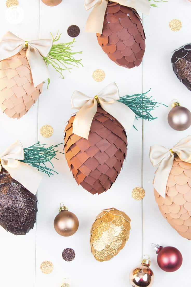 Learn how to make paper pinecone ornaments that you can use to decorate your Christmas tree or for packaging gifts. The ornaments are made by applying small paper squares or circles on polystyrene eggs. You can choose any size of egg shape and use a wide variety of papers for the scales, such as cardstock, scrapbook paper, glitter paper, or gift wrap. We also demonstrate how to make pine needles form crepe paper to decorate the ornaments. #DIY #pinecone #papercrafts | countryhillcottage.com