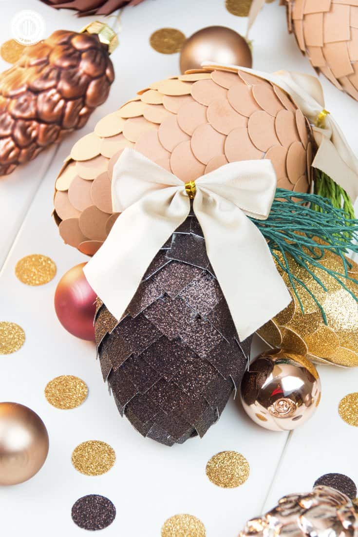 Learn how to make paper pinecone ornaments that you can use to decorate your Christmas tree or for packaging gifts. The ornaments are made by applying small paper squares or circles on polystyrene eggs. You can choose any size of egg shape and use a wide variety of papers for the scales, such as cardstock, scrapbook paper, glitter paper, or gift wrap. We also demonstrate how to make pine needles form crepe paper to decorate the ornaments. #DIY #pinecone #papercrafts | countryhillcottage.com