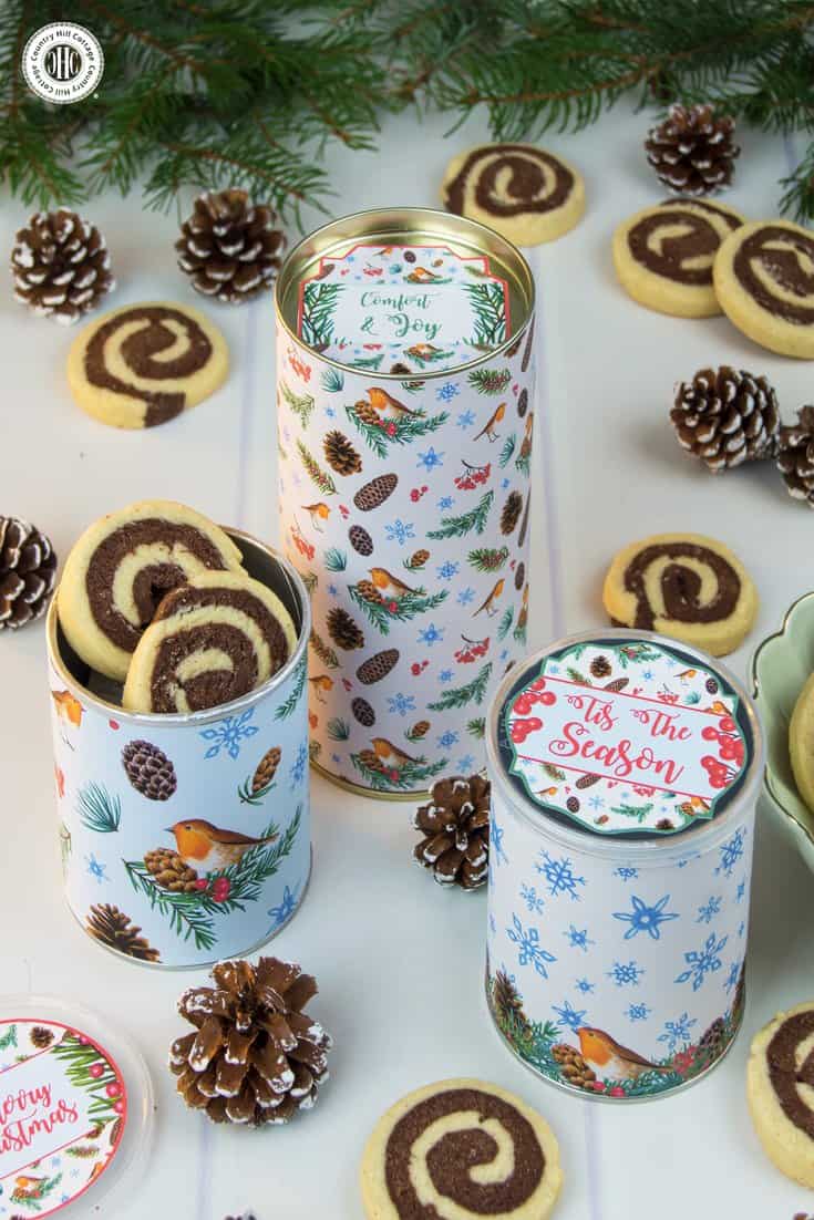 Festive upcycling at its finest! Repurpose empty cookie or crisp canisters into a gorgeous cookie giftable. Glue sheets of decorative pattern to the tins (cans). This process is even easier when you print the pattern on self-adhesive paper. We also used gift tags to decorate the lids. Get this and 10 more cookie packaging ideas! #Christmas #foodgifts #cookiepackaging #freebie | countryhillcottage.com