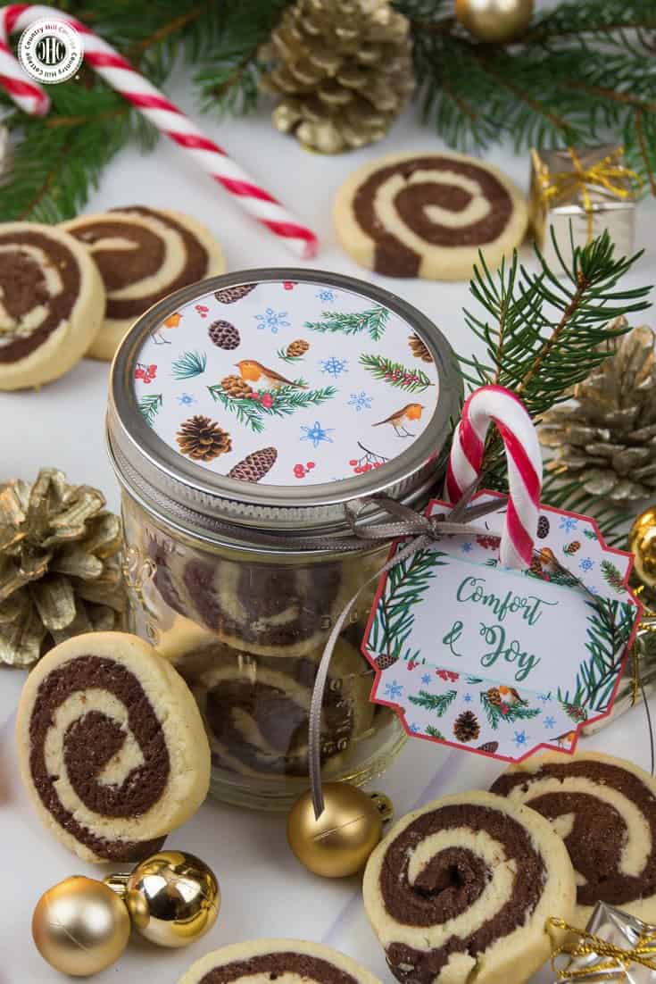 Put your cookies on display in shiny mason jars. We decorated the lid with a circle cut of decorative pattern, and tied a gift tag, candy cane, and twig to the jar. Get this and 10 more cookie packaging ideas! #Christmas #foodgifts #cookiepackaging #freebie | countryhillcottage.com