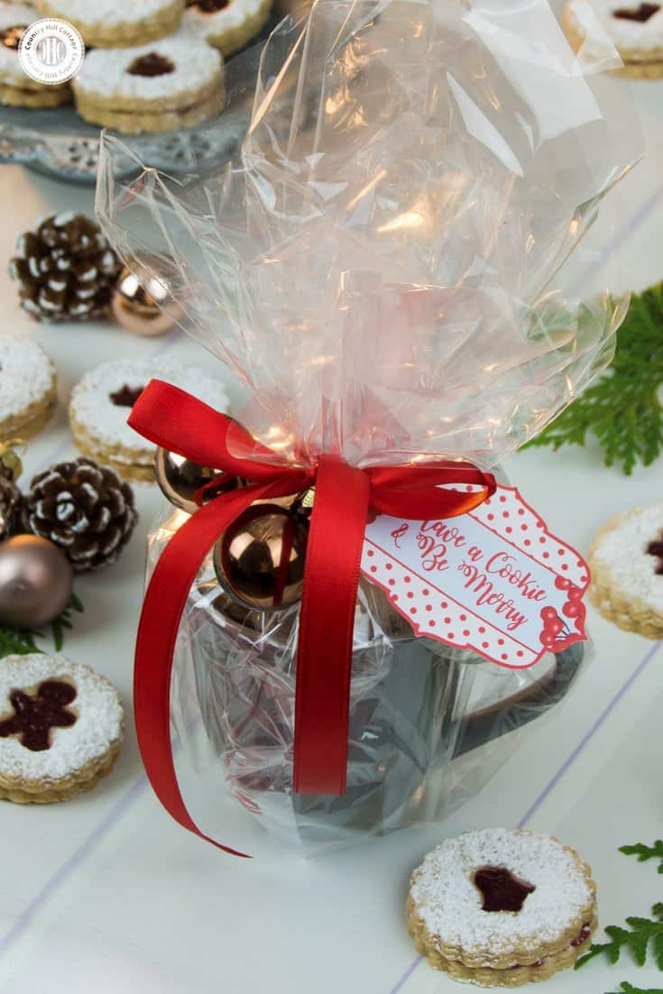 This one is a lovely two-in-one gift! Transform mugs, cups, and bowls into beautiful storage and a pop of colour with ribbon, mini bauble ornaments, and a gift tag. Simply, place the cup or mug in the middle of a large square of cellophane, gather the edges of the cellophane, and tie with a ribbon to secure. Get this and 10 more cookie packaging ideas! #Christmas #foodgifts #cookiepackaging #freebie | countryhillcottage.com