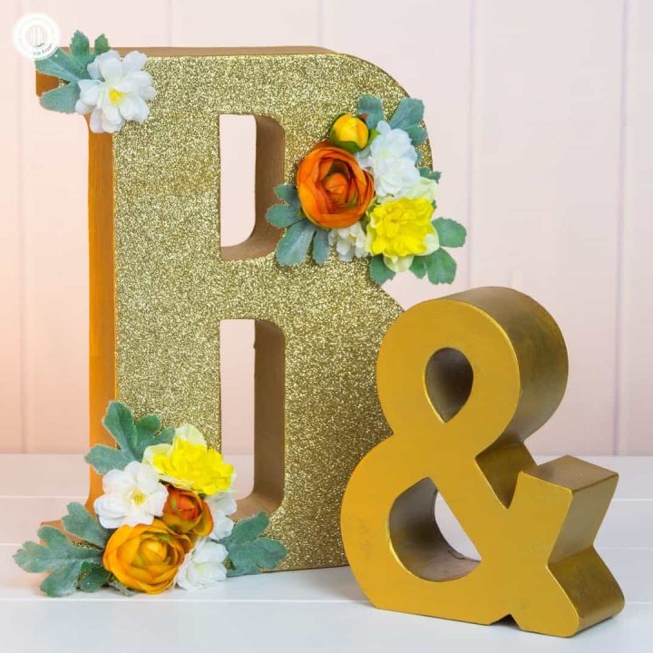 Learn how to how to make glitter wedding letters! We use large paper mache letters and show different techniques to paint the letters, apply glitter and decorate them with silk flowers. Monogram letters make fabulous wedding décor to display the initials of the bride and groom. You can use them as table decoration or hang them as a wall ornament. #diy #wedding #decor #glitter #monogram | countryhillcottage.com