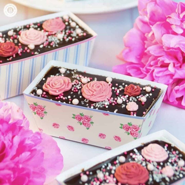Rosewater tea cakes with a rich chocolate ganache glaze are the perfect treat to enjoy with a hot, strong cuppa, serve at a bridal shower, or gift to Mum on Mother’s Day. The cakes are made with a quick one-bowl batter and topped with a rosewater-infused chocolate ganache. The loaves are decorated with edible sugar roses, and we put them in free printable loaf wrappers from our Vintage Rose collection. #rosewater #teacakes #cupcakes #chocolateganache #sugarroses | countryhillcottage.com