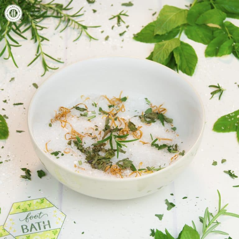 A homemade foot bath is a wonderful DIY spa experience! You can set up a foot bath in preparation for a mani-pedi, to soothe swollen feet on a hot summer day, or to soften foot calluses and corns. The base is made with Epsom salt, a magnesium sulfate compound known to reduce inflammation, relieve pain and eliminate odour. Tea tree oil helps to soften calluses, while peppermint oil and rosemary soothe cracked, dry skin. #footbath #epsomsalt #essentialoils #beautyrecipe | countryhillcottage.com