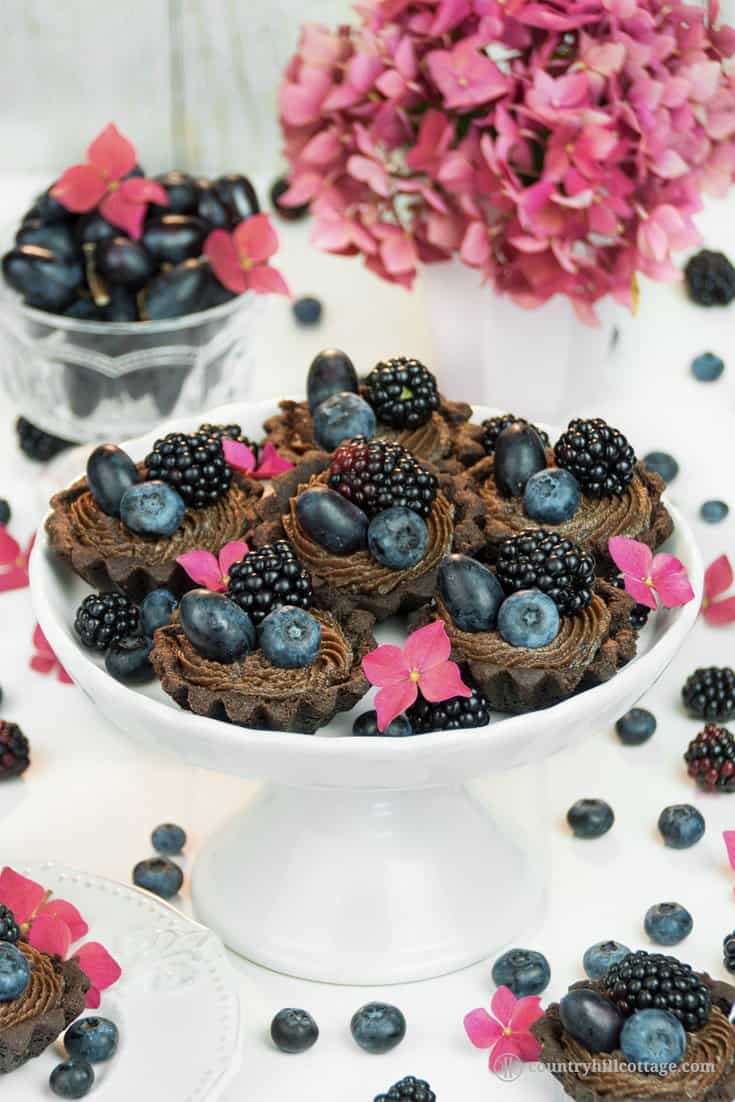 For a lovely afternoon tea indulgence bake delicious chocolate tartlets with berries! Crisp chocolate shells are laden with dark summer berries and filled with a delectable chocolate cream cheese filling with subtle berry notes. The dough is soft, crumbly and has an intense chocolate flavour. The soft filling is made with cream cheese, white and dark chocolate and blueberry jam to reflect the berry decoration. #tartlet #chocolate #tart #berries #bakingrecipe | countryhillcottage.com For a lovely afternoon tea indulgence bake delicious chocolate tartlets with berries! Crisp chocolate shells are laden with dark summer berries and filled with a delectable chocolate cream cheese filling with subtle berry notes. The dough is soft, crumbly and has an intense chocolate flavour. The soft filling is made with cream cheese, white and dark chocolate and blueberry jam to reflect the berry decoration. #tartlet #chocolate #tart #berries #bakingrecipe | countryhillcottage.com