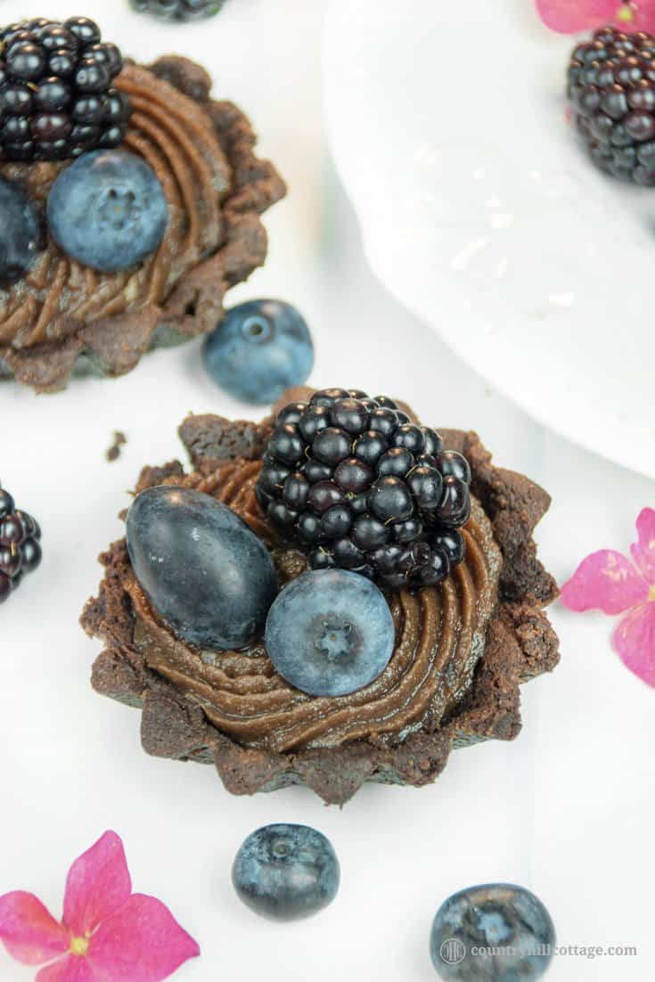 For a lovely afternoon tea indulgence bake delicious chocolate tartlets with berries! Crisp chocolate shells are laden with dark summer berries and filled with a delectable chocolate cream cheese filling with subtle berry notes. The dough is soft, crumbly and has an intense chocolate flavour. The soft filling is made with cream cheese, white and dark chocolate and blueberry jam to reflect the berry decoration. #tartlet #chocolate #tart #berries #bakingrecipe | countryhillcottage.com For a lovely afternoon tea indulgence bake delicious chocolate tartlets with berries! Crisp chocolate shells are laden with dark summer berries and filled with a delectable chocolate cream cheese filling with subtle berry notes. The dough is soft, crumbly and has an intense chocolate flavour. The soft filling is made with cream cheese, white and dark chocolate and blueberry jam to reflect the berry decoration. #tartlet #chocolate #tart #berries #bakingrecipe | countryhillcottage.com