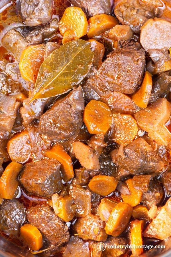 This easy beef stew recipe makes a sumptuous supper and is perfect for cheaper cuts. Our traditional braised beef stew is made with root veggies, fresh herbs, red wine and tasty broth. A slow cooking time guarantees tender meat and a flavourful gravy. The recipe includes instructions for cooking the beef stew on a stove top, in the oven or slow cooker, as well as tips for the type of beef cut you need, seasoning and other ingredients. #beef #stew #beefstew #stewrecipe | countryhillcottage.com