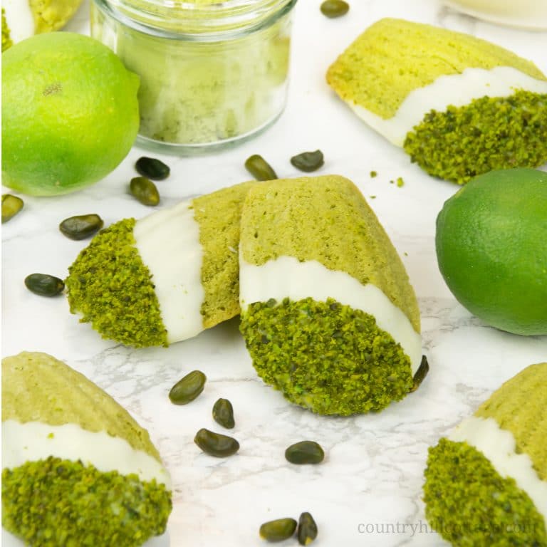 Chocolate-dipped pistachio lime matcha madeleines. Velvety and fluffy, these homemade madeleines are flavoured with matcha powder, pistachios, lime, and a touch of honey, and generously dipped in white chocolate. These make an excellent food gift and are perfect for tea time and so many other occasions. The recipe isn’t difficult at all, and every last crumb is of these madeleines is melt-in-your-mouth deliciousness. #matcha #madeleines #matchamadeleines #foodgifts | countryhillcottage.com