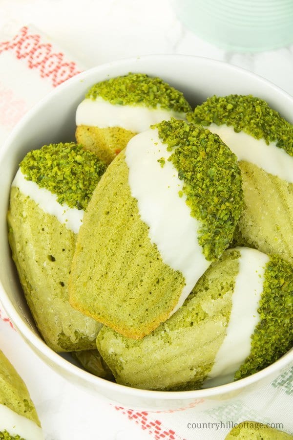 Chocolate-dipped pistachio lime matcha madeleines. Velvety and fluffy, these homemade madeleines are flavoured with matcha powder, pistachios, lime, and a touch of honey, and generously dipped in white chocolate. These make an excellent food gift and are perfect for tea time and so many other occasions. The recipe isn’t difficult at all, and every last crumb is of these madeleines is melt-in-your-mouth deliciousness. #matcha #madeleines #matchamadeleines #foodgifts | countryhillcottage.com Chocolate-dipped pistachio lime matcha madeleines. Velvety and fluffy, these homemade madeleines are flavoured with matcha powder, pistachios, lime, and a touch of honey, and generously dipped in white chocolate. These make an excellent food gift and are perfect for tea time and so many other occasions. The recipe isn’t difficult at all, and every last crumb is of these madeleines is melt-in-your-mouth deliciousness. #matcha #madeleines #matchamadeleines #foodgifts | countryhillcottage.com