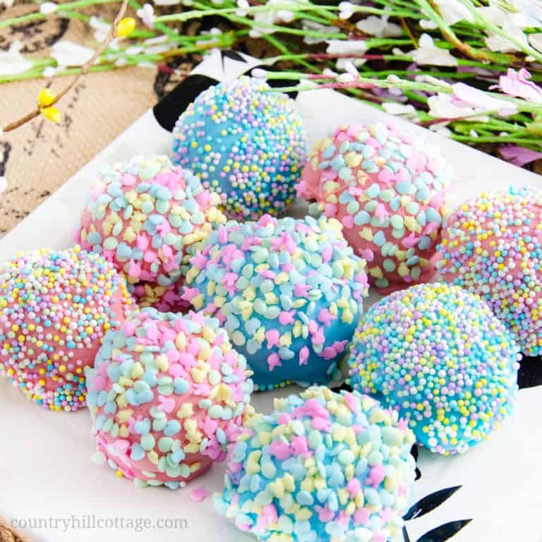 These sweet, delicious carrot cake bites are perfect Easter treats and basket stuffers with their bright colors and Easter sprinkles. The cake bites are easy to make. The recipe uses boxed cake mix, with adjustments to make it taste homemade, and a yum cinnamon cream cheese frosting. The bites are dipped in pastel candy melts and covered with sprinkles. Your friends and family will love this homemade food gift. #cakebites #Eastertreat #Easter #sprinkles #cakepops | countryhillcottage.com