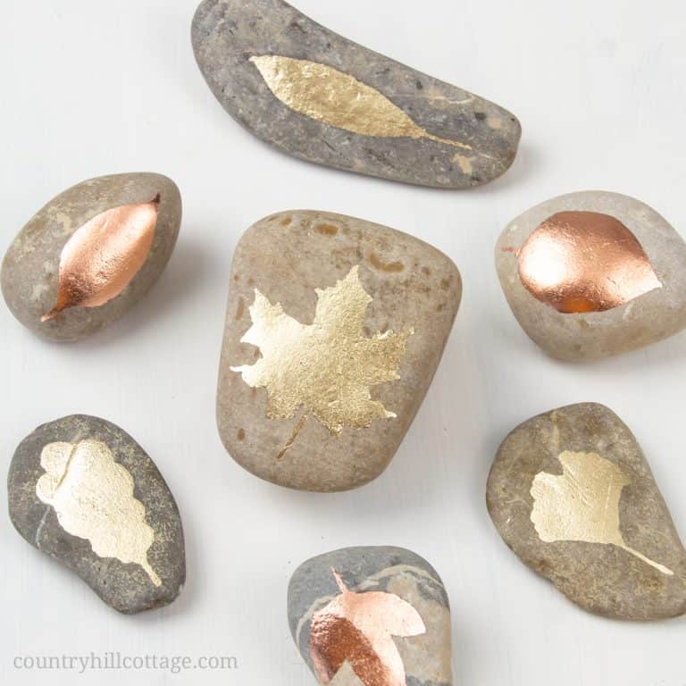 Shiny DIY Gold Leaf Painted Rocks are very easy to make and a lovely pebble art idea. This quick and simple 15 minutes rock painting tutorial includes step by step instructions, tips for supplies and is excellent for beginners. The nature-inspired leaf design is beautiful fall decor and a pretty handmade craft idea to gift or sell. This rock painting inspiration is a great DIY craft project for teens and adults. #paintedrock #rockpainting #goldleaf #pebbleart #tutorial | countryhillcottage.com