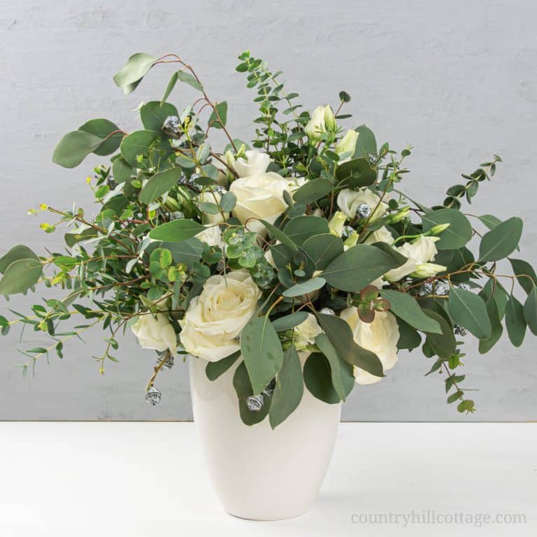 See how to make an easy and modern DIY eucalyptus arrangement in a vase! This homemade fresh flower design is made with different types of eucalyptus, including silver dollar, baby blue and seeded, and stunning white flowers. The simple large vase arrangement is beautiful as farmhouse home decor and could also be transformed into tall wedding center pieces for receptions. The step-by-step tutorial also includes tips for faux/fake and dry greenery. #eucalyptus #homedecor| countryhillcottage.com