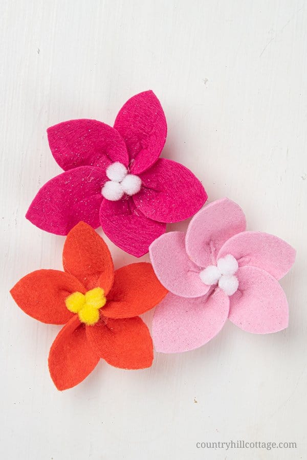 How to make a felt poinsettia – Easy DIY felt flower tutorial for Christmas and the holidays. See how to make a festive DIY Christmas felt wreath! Creating your own homemade Christmas wreath with felt is super easy and fun. This handmade holiday felt craft comes with free printable pattern templates and SVG files for Cricut. Great for decorations, jewelry, craft projects. #felt #feltflowers #feltflowerwreath #poinsettia #feltcraft | countryhillcottage.com