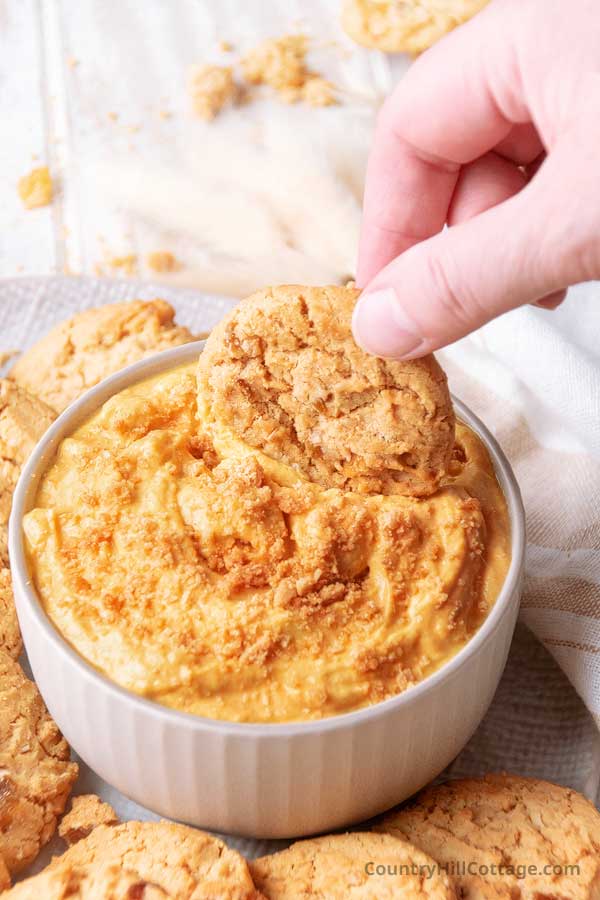 hand scooping up easy pumpkin dip from a bowl.
