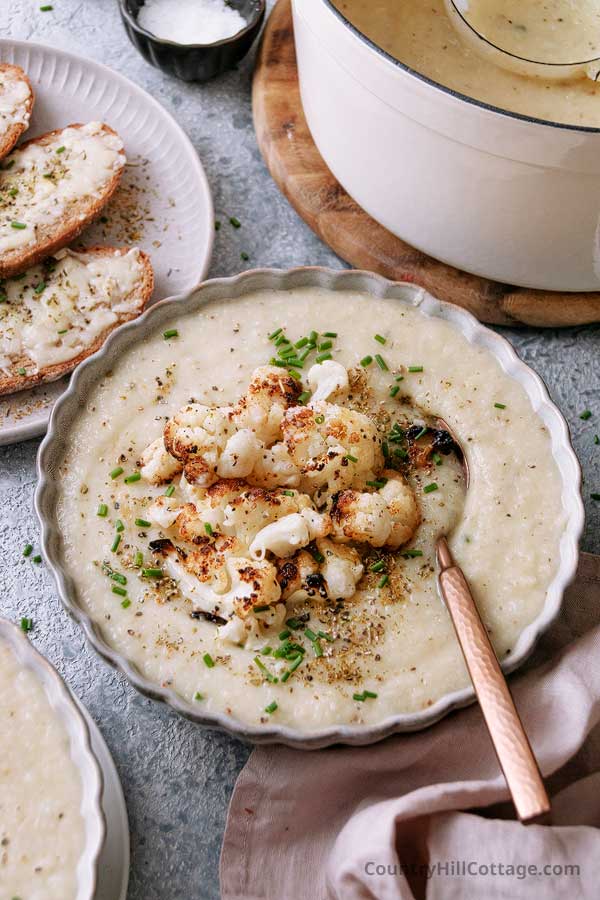bowl of easy no cream cauliflower soup with a spoon and topped with roasted cauliflower.