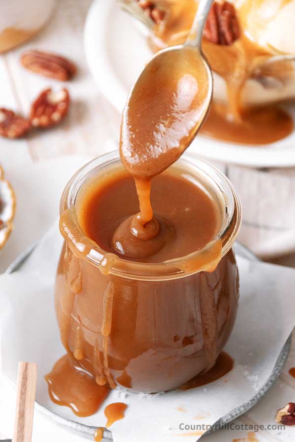 spoon dipping into a jar of evaporated milk caramel sauce.