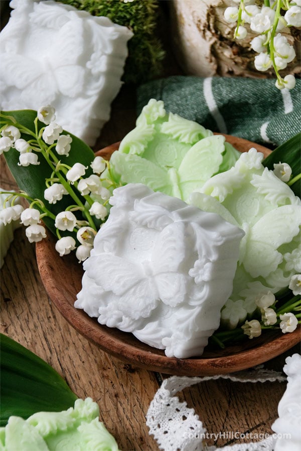 close-up of green lily of the valley soap bars in a wooden bowl.